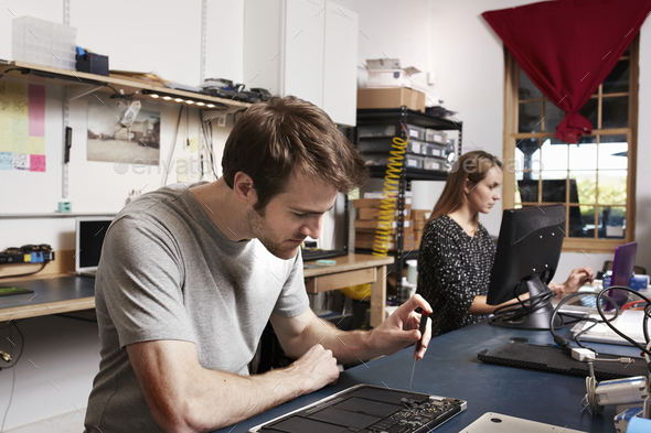 A young man and woman working at a bench in a technology lab.