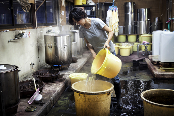 Japanese woman working in a textile plant dye workshop, pouring hot water into yellow plastic