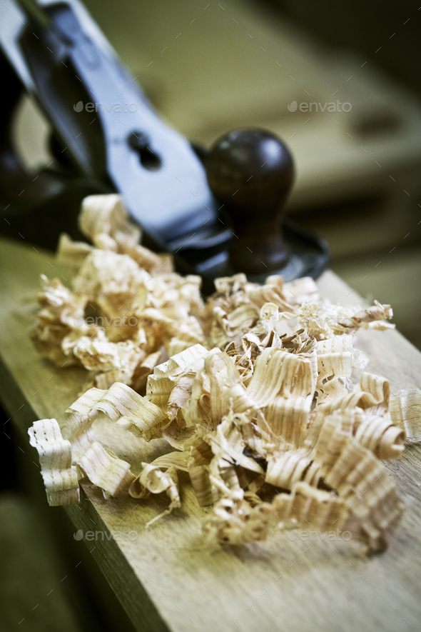 A wood plane on a piece of wood and wood shavings.