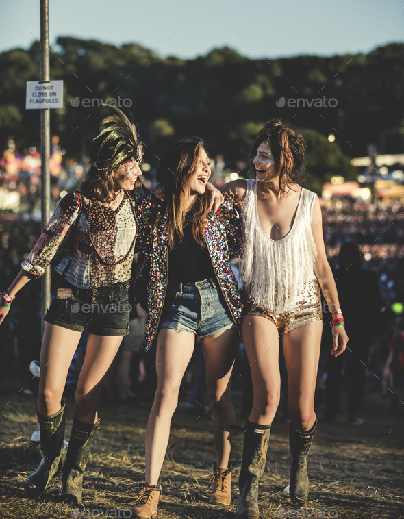 Three young women at a summer music festival wearing hot pants and Wellington boots, feather - Stock Photo - Images