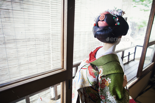 A woman dressed in the traeditional geisha style, wearing a kimono and obi, with an elaborate - Stock Photo - Images