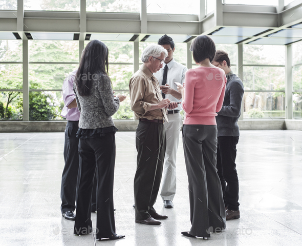 A mixed race group of male and female business people standing in the lobby area of a convention - Stock Photo - Images