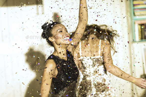 Two young women dancing with confetti falling.