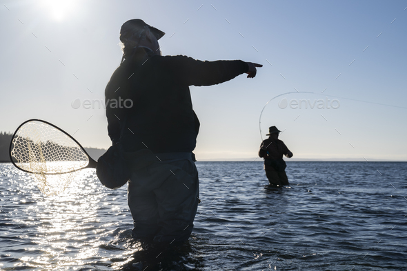 A guide advises his client while fly fishing in salt water for searun coastal cutthroat trout and - Stock Photo - Images
