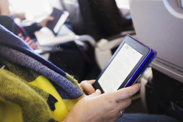 A passenger on an aircraft using a digital tablet.