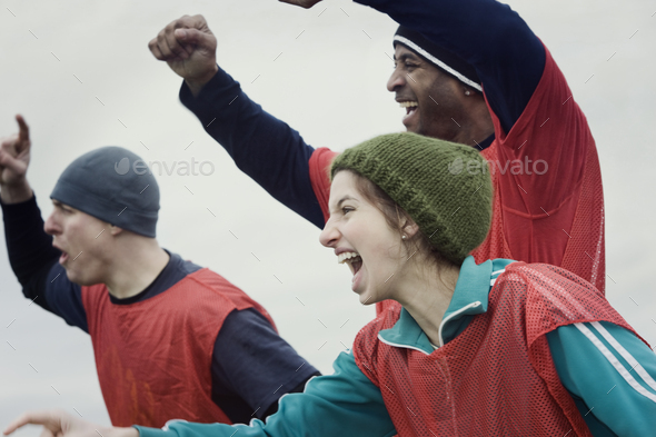 Two men and one woman, friends cheering on their team at a winter sporting event.