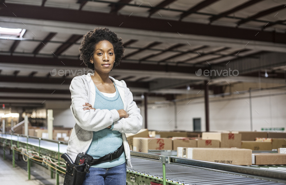 Portrait of an African American female warehouse worker in a large distribution warehouse with - Stock Photo - Images