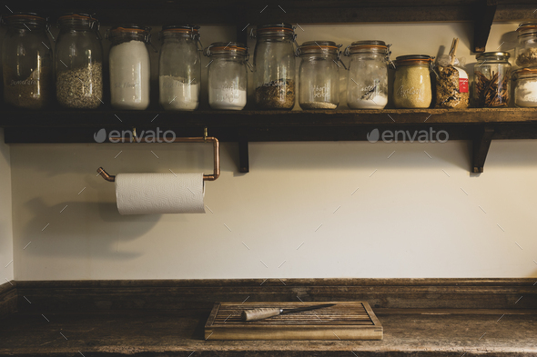 Wooden chopping board and knife on vintage wooden kitchen cupboard, row of glass jars with cooking - Stock Photo - Images