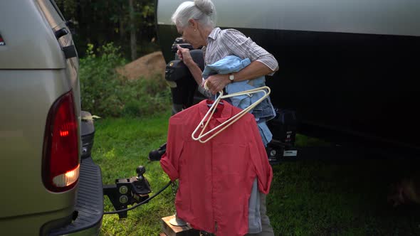 Elderly man adjusts his recreational vehicle to get it coupled with his truck. alt