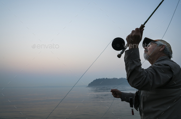 Senior Caucasian male fly fishing for salmon and sea run cutthroat trout in  Puget Sound near Port Stock Photo by Mint_Images