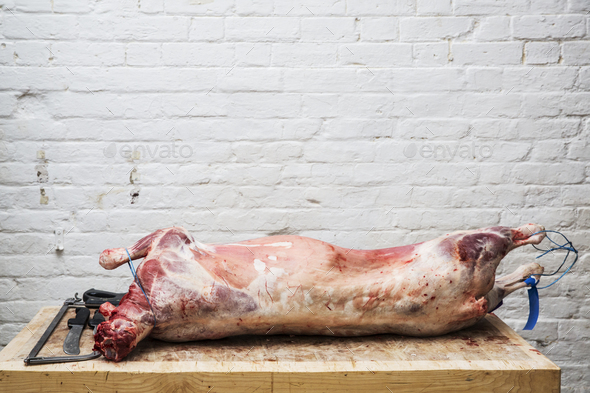 A whole lamb carcass on a butcher\'s block ready for butchering.