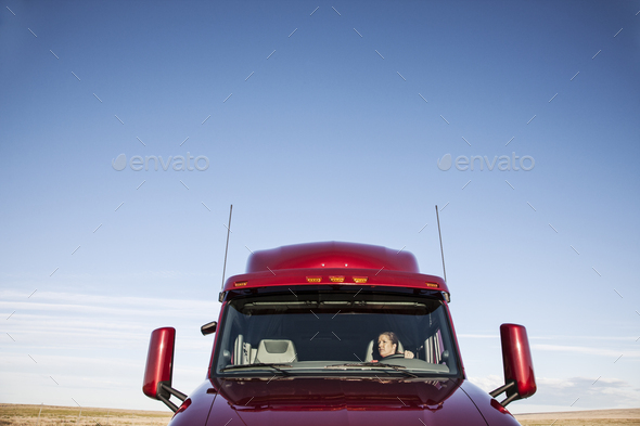 View of a Caucasian woman driver in the cab of her commercial truck.