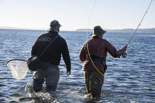 A guide advises his client while fly fishing in salt water for searun coastal cutthroat trout and - Stock Photo - Images