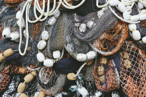 Close up of a pile of tangled up commercial fishing nets with floats  attached. Stock Photo by Mint_Images