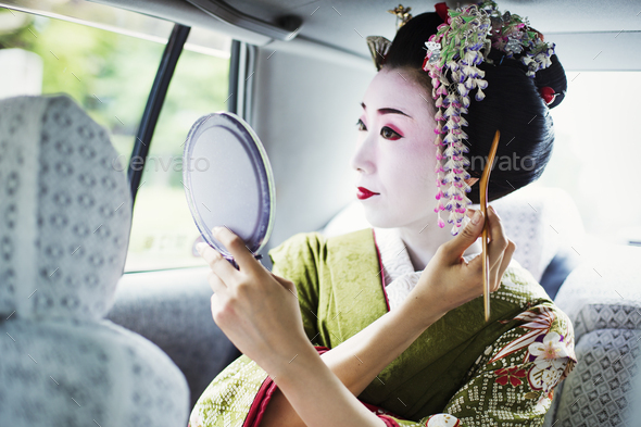 A woman dressed in the traditional geisha style, wearing a kimono and obi, with an elaborate - Stock Photo - Images