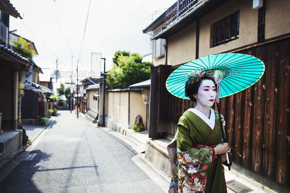 A woman dressed in the traditional geisha style, wearing a kimono and obi, with an elaborate - Stock Photo - Images