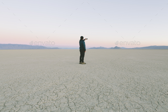 Man taking photo with smart phone, standing in vast desert playa, Black Rock Desert, Nevada - Stock Photo - Images