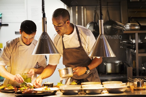 Two chefs standing in a restaurant kitchen, plating food. - Stock Photo - Images