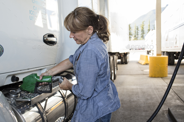 Caucasian woman truck driver filling truck with diesel fuel at a truck stop.