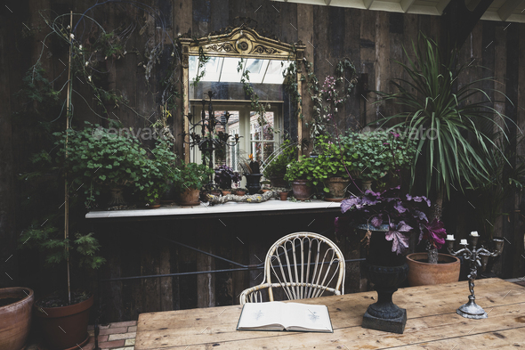 Garden room with wooden walls, rustic wooden table and antique mirror with ornate gilded frame,