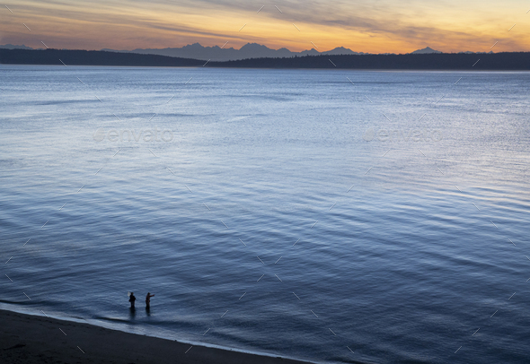 A view from above of a guide and a fly fisherman at the water's edge, fishing for salmon and sea run - Stock Photo - Images