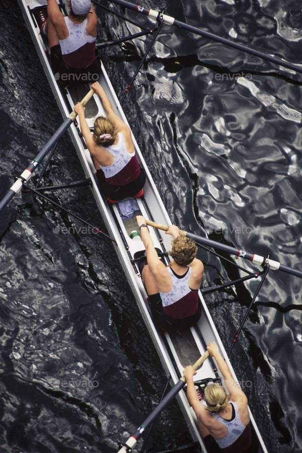 Overhead view of female crew racers rowing scull boat.
