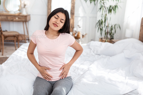 Asian Girl Having Touching Stomach Suffering From Menstrual Cramps Indoors - Stock Photo - Images