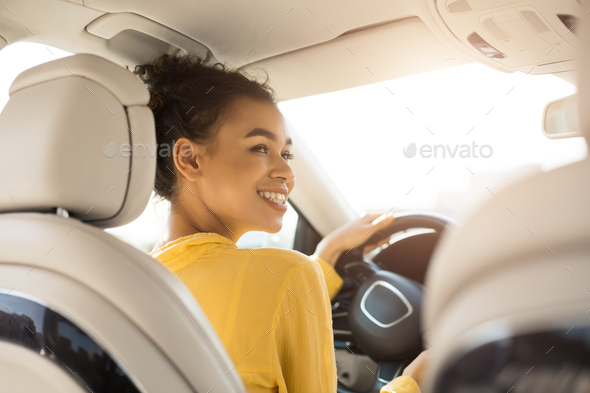 Cheerful Black Woman Driving Car Sitting In Automobile, Back View