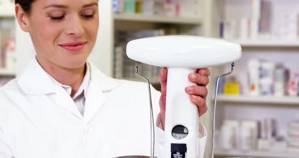 Pharmacist measuring tablets with pharmacy scale alt