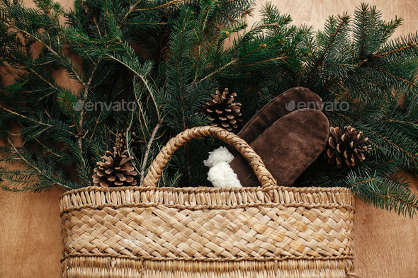 Rustic basket with fir branches, cozy gloves, cones on rustic wooden background - Stock Photo - Images