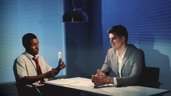 African Police Detective Showing Photos of the Person, but the Suspect Criminal Does Not Recognize alt