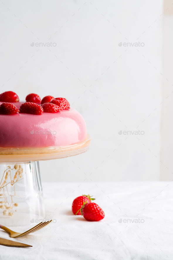 Freshly prepared homemade fruit glazed pink dessert decorated strawberries on a glass dish against - Stock Photo - Images