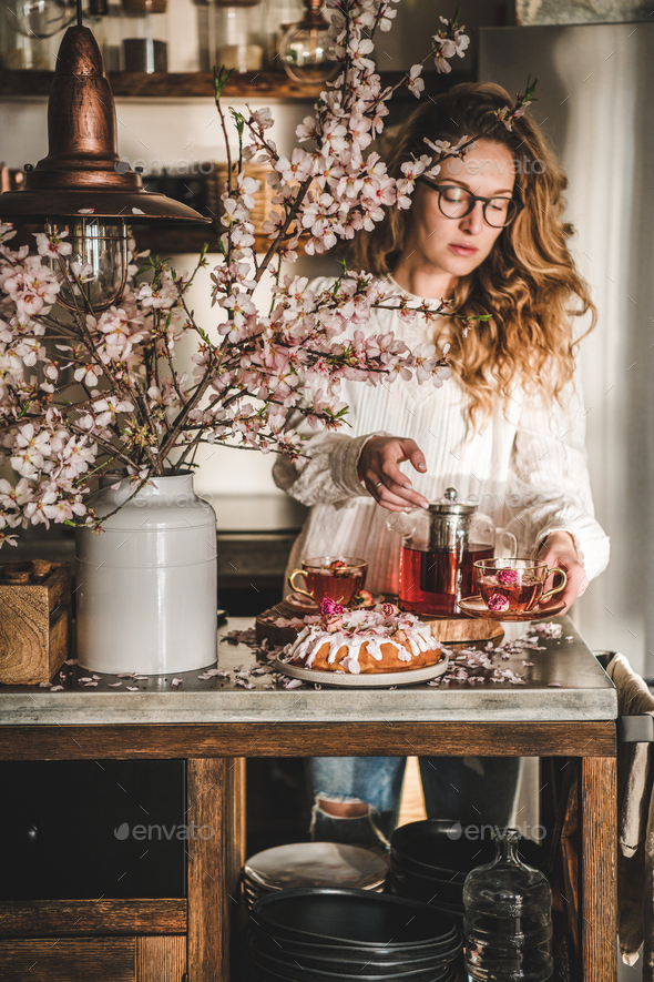Young woman serving homemade bundt cake and tea in kitchen - Stock Photo - Images
