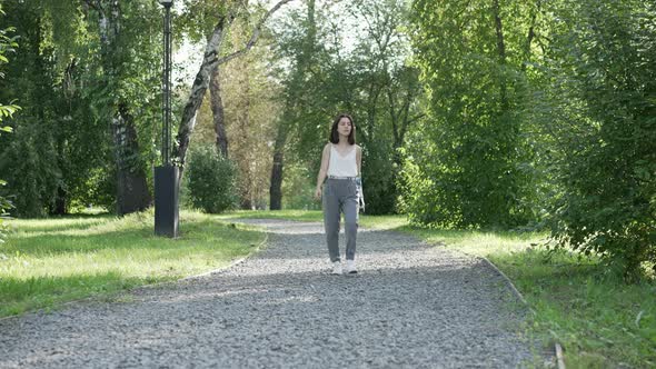 Girl with bionic prosthesis is walking on park Bionics Cybernetic Robotic-arm Hand prosthesis alt