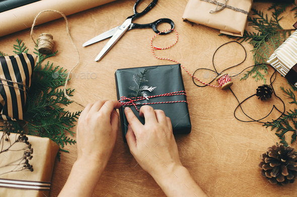 Hands wrapping stylish christmas gift box in black paper - Stock Photo - Images