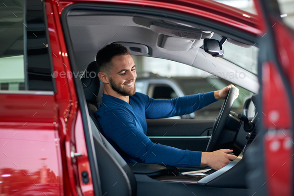 Happy male customer in car in dealership