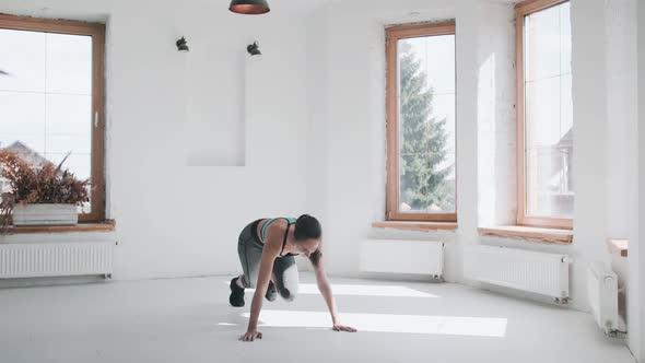 Attractive Young Fit Girl in Sportswear Running Plank in Bright Room at Home