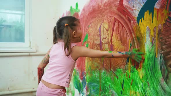 Little Girl Child Preschooler Draws Hands Paints On White Wall. alt