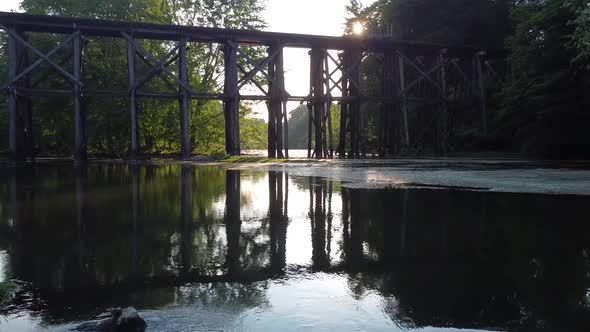 Aerial Flying Over Dam with Waterfalls Low to River Towards Old Railroad Bridge alt