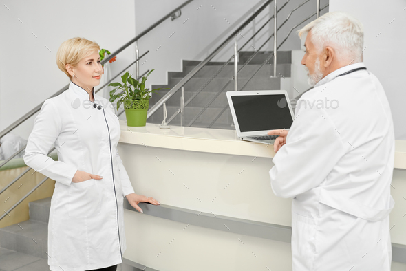 Female doctor talking with coworker near hospital reception