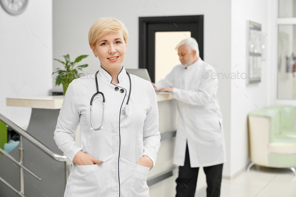 Female doctor in coat keeping hands in pockets - Stock Photo - Images