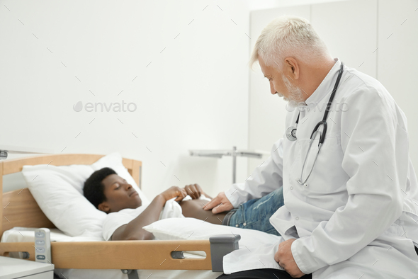 Eldery doctor examinating belly of african patient - Stock Photo - Images
