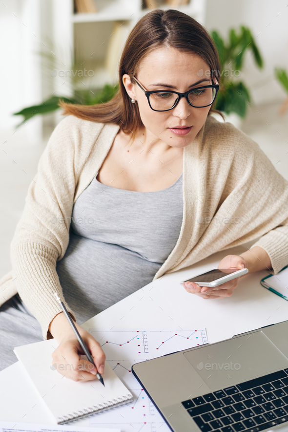 Pretty pregnant analyst or broker using mobile gadgets while comparing data - Stock Photo - Images