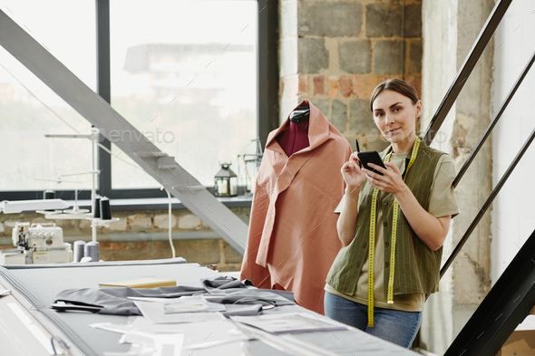 Happy young tailor and owner of fashion studio taking new orders from clients - Stock Photo - Images