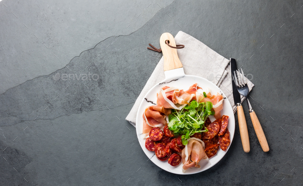 Spanish ham serrano and salami on white marbled plate. Top view. Copy space. - Stock Photo - Images