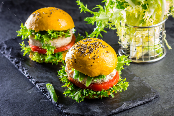 Colored yellow burgers. Chicken burgers hamburgers with turmeric bread - Stock Photo - Images