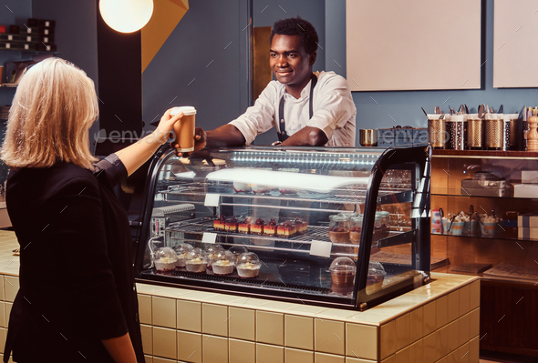 Download African American barista in uniform giving a cup of coffee ...