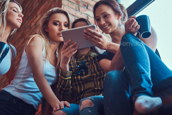 Group of female friends discussing while looking something on a digital tablet in a apartment - Stock Photo - Images
