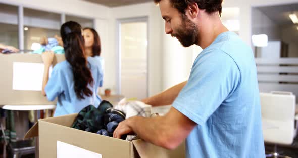 Male Volunteer Packing Clothes in Donation Box alt
