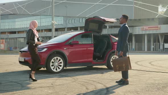 Female Seller and Male Client Standing Near Electric Car and Discussing All alt